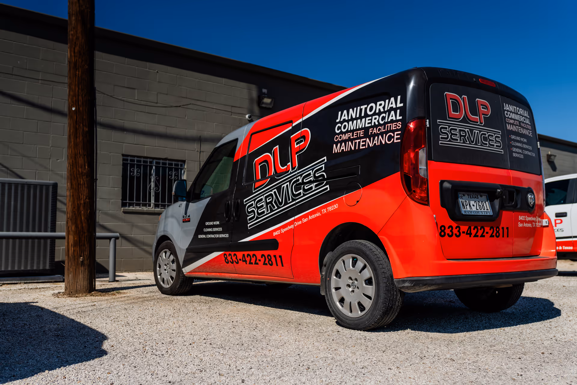 Red and black DLP Services van parked beside a gray exterior building.