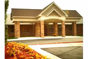 Front exterior view of Medilodge of Capital Area entrance with brick columns and a covered drop-off.
