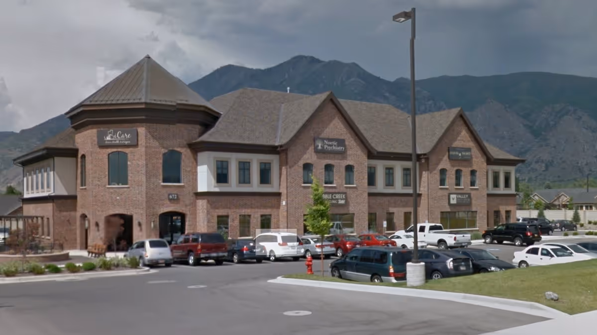 Brick iCare Home Health and Hospice building with cars in parking lot and mountains in background.