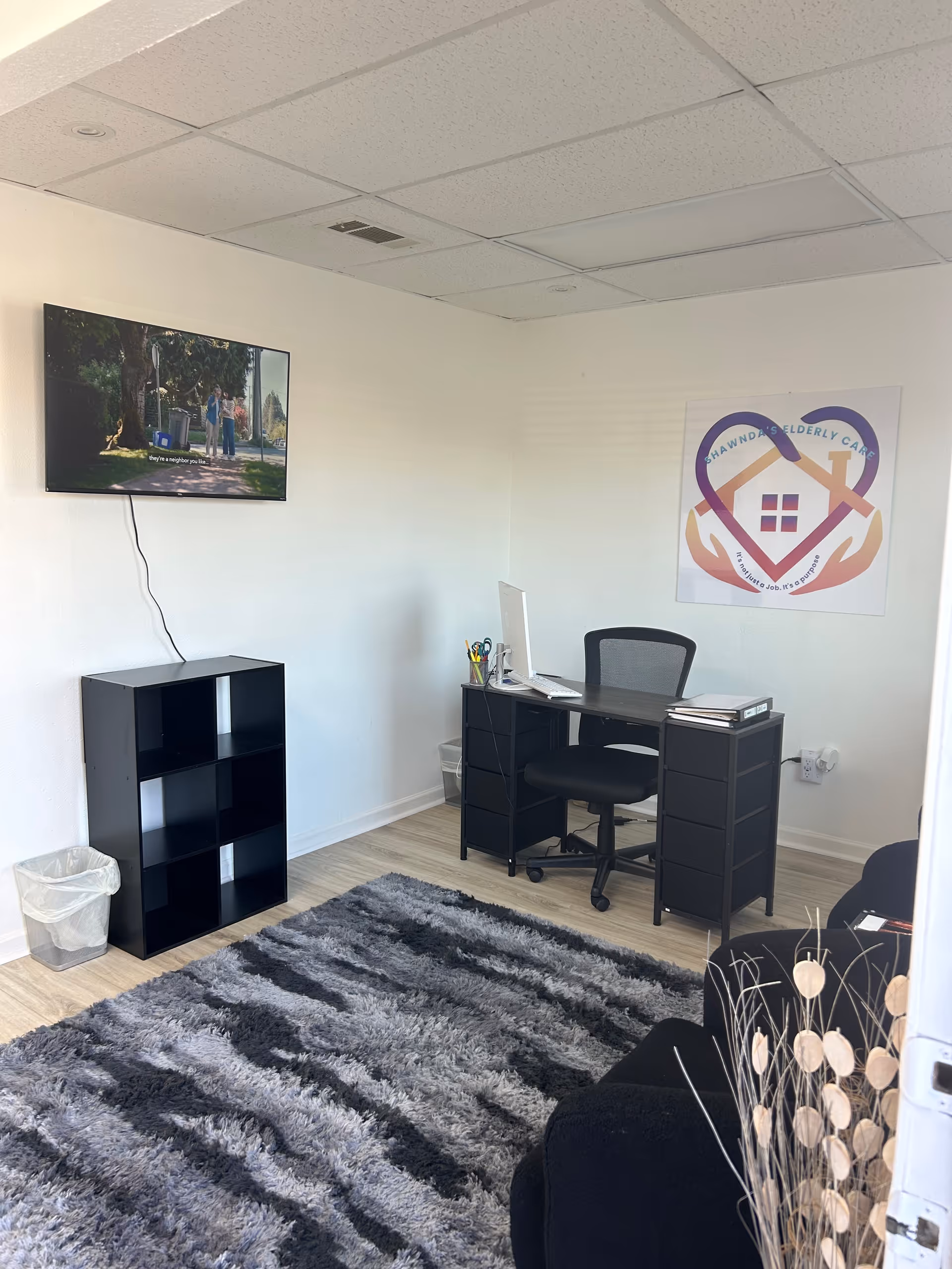 Small office in a senior care facility with desk, computer, TV, and poster.