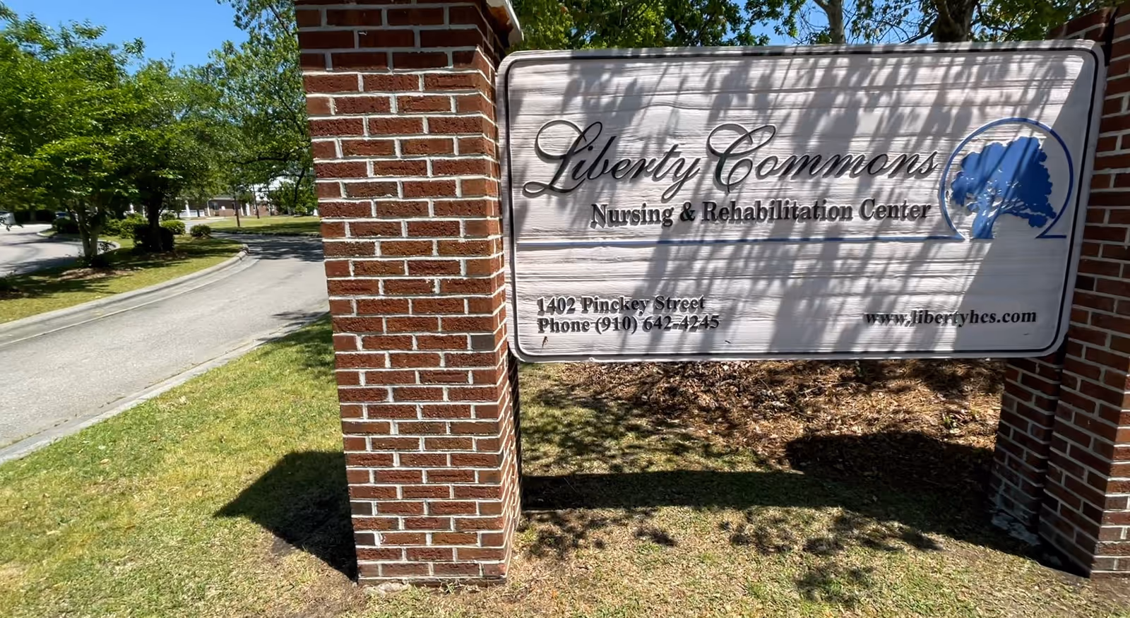 Exterior sign for Liberty Commons Nursing & Rehabilitation Center on brick pillars.