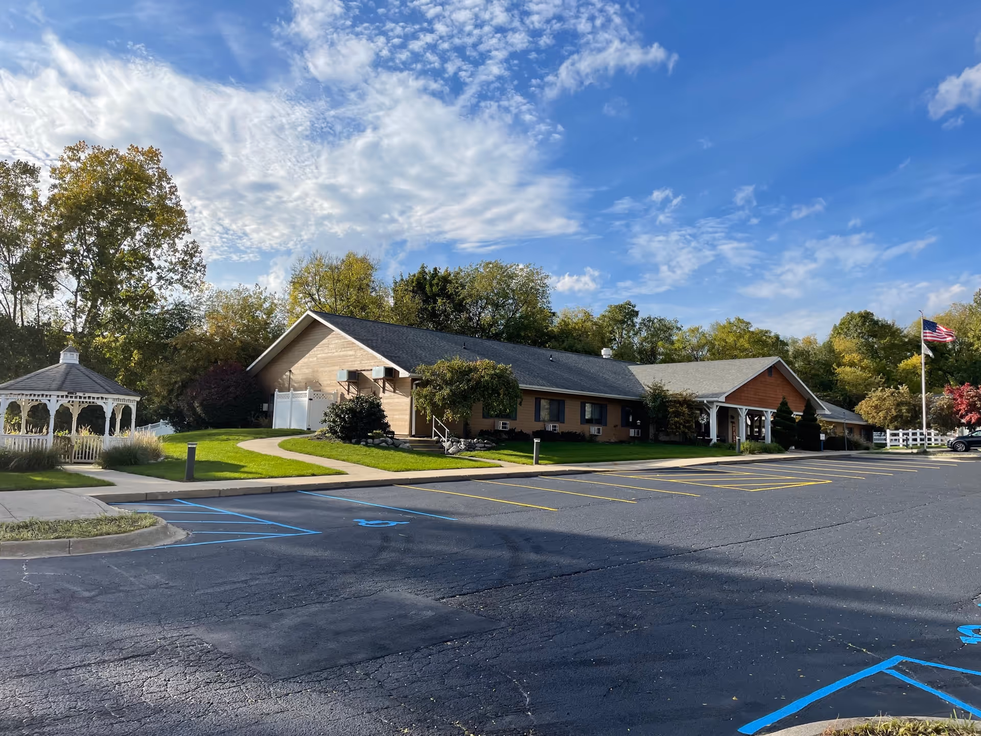 Exterior view of a single-story senior care center with parking and a gazebo.