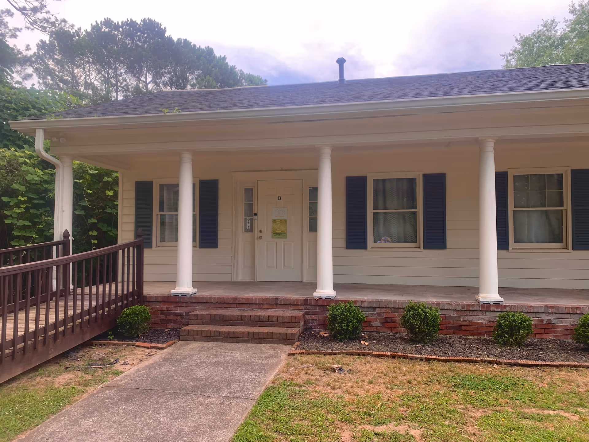 Front view of a single-story AMOR Home Care building with a porch and columns.