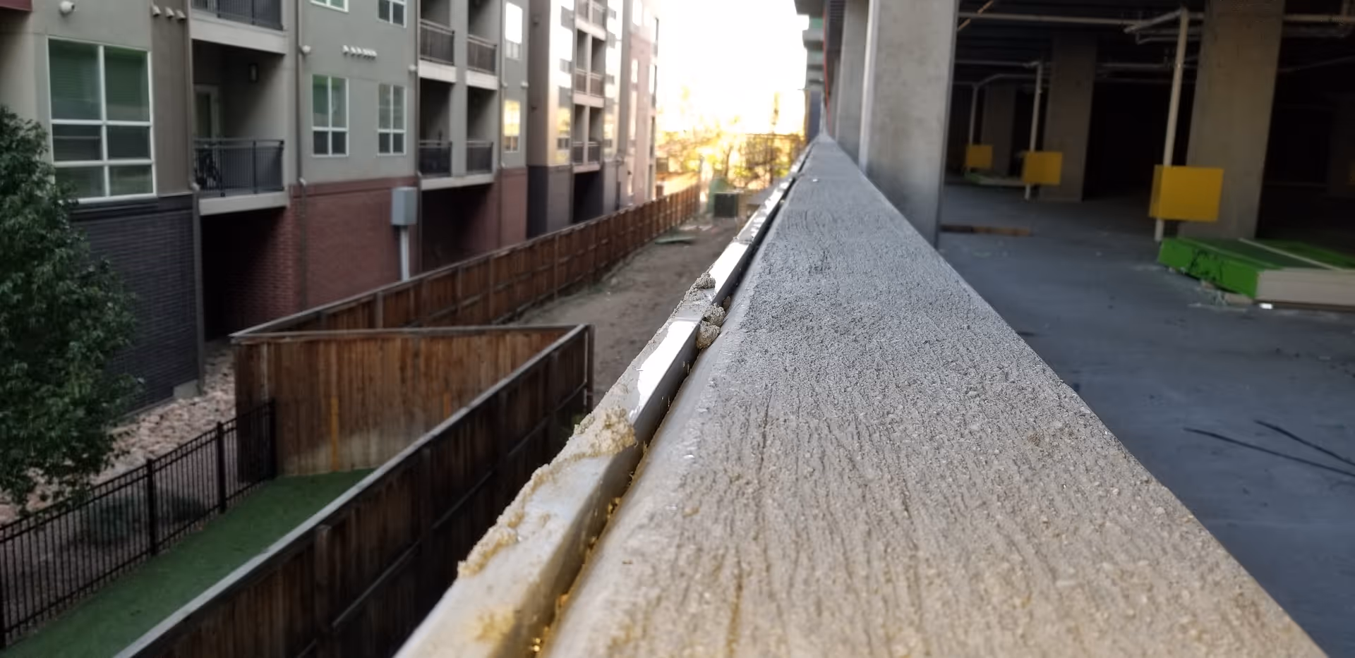Long concrete railing over a walkway between apartment-style buildings, no people visible.