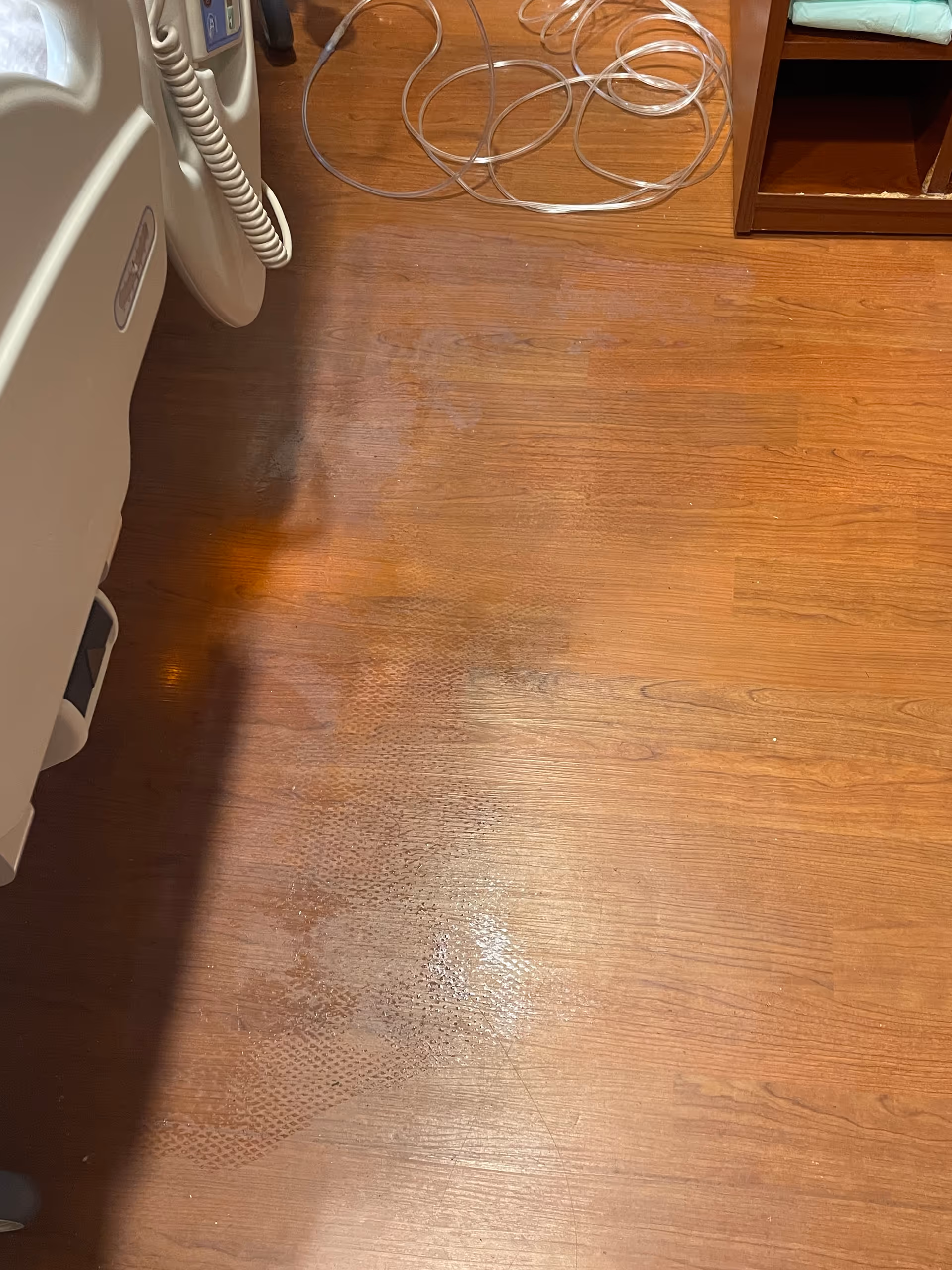 Wood floor, medical equipment, and tangled cables in a clinical room.