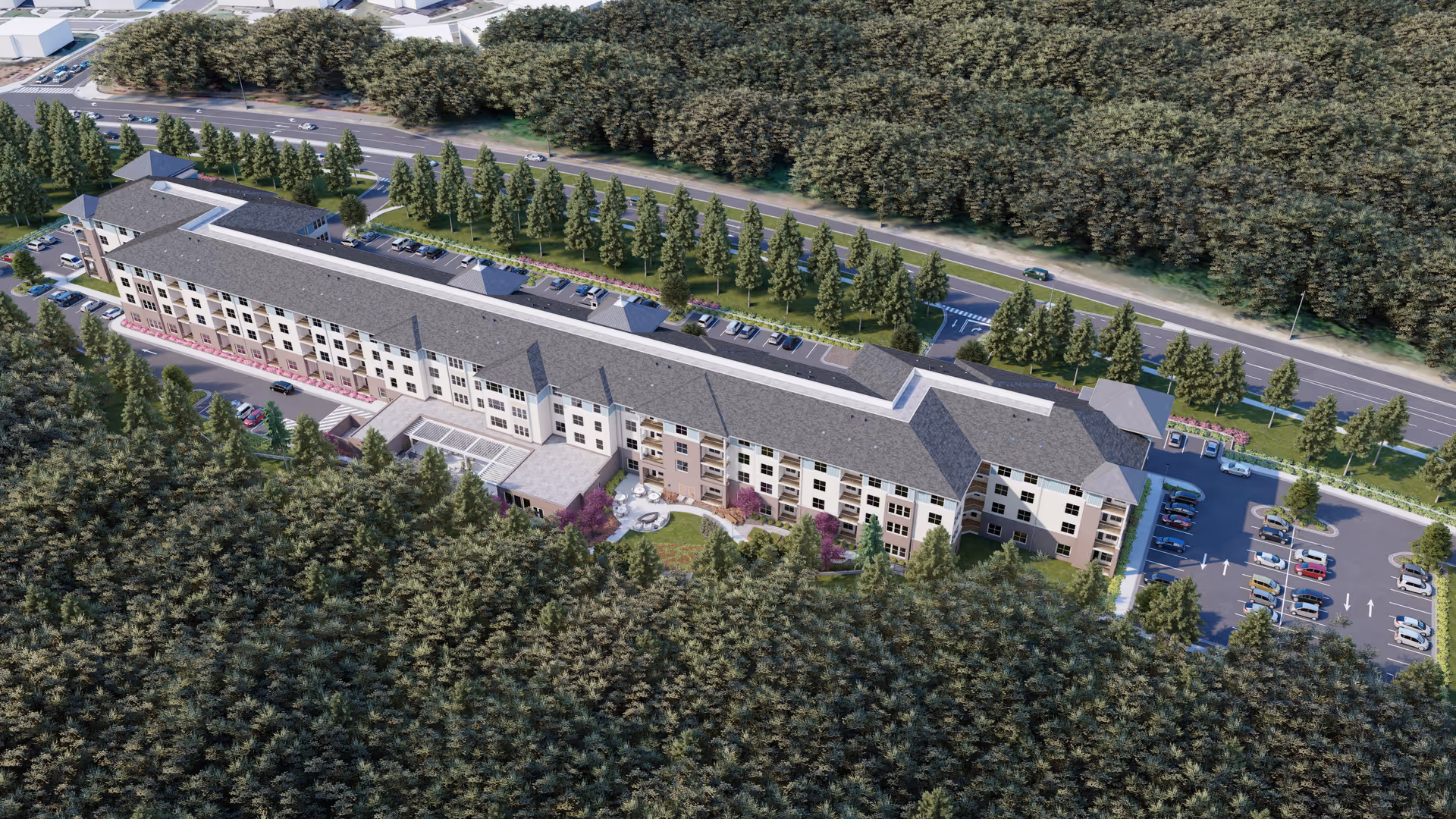 Aerial view of a large senior living facility named Acclaim at Cary Pointe surrounded by dense trees. The building is long and rectangular with multiple floors, parking lots on both sides, and a landscaped courtyard with seating areas. A road runs parallel to the building with cars driving by.