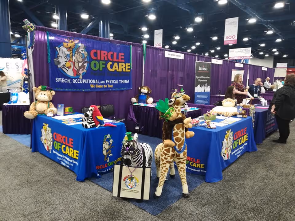 Indoor expo booth for Circle of Care with blue tablecloths and plush animals.