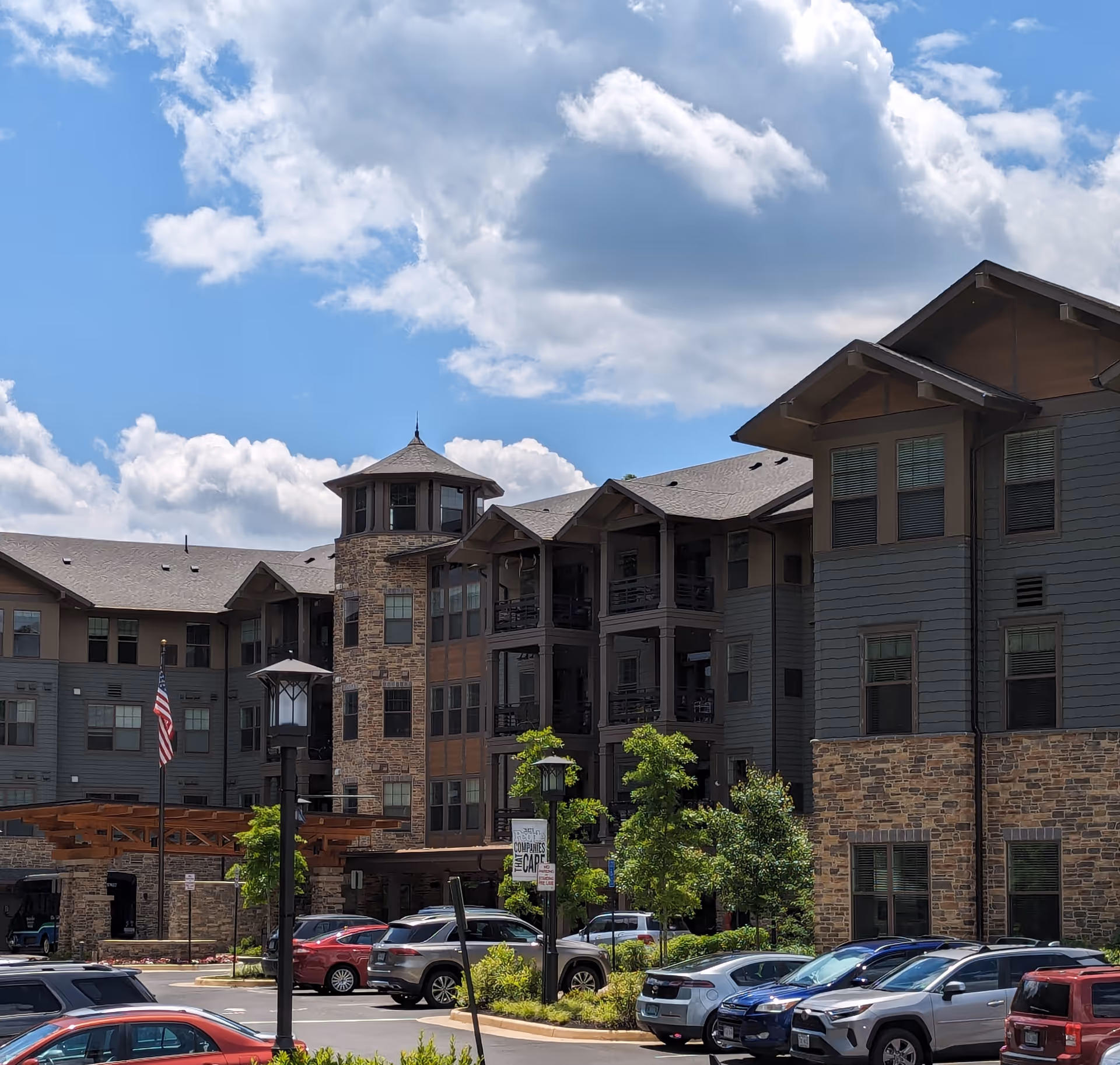 Multi-story senior living building with stone accents, balconies, and a parking lot.