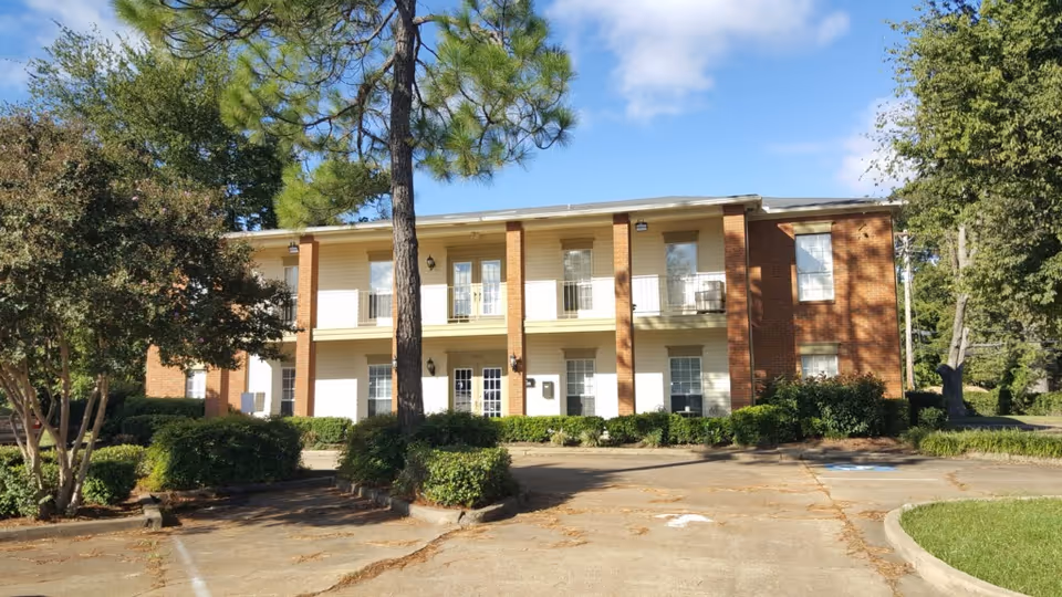 Two-story brick senior care building with front entrance and surrounding landscaping.