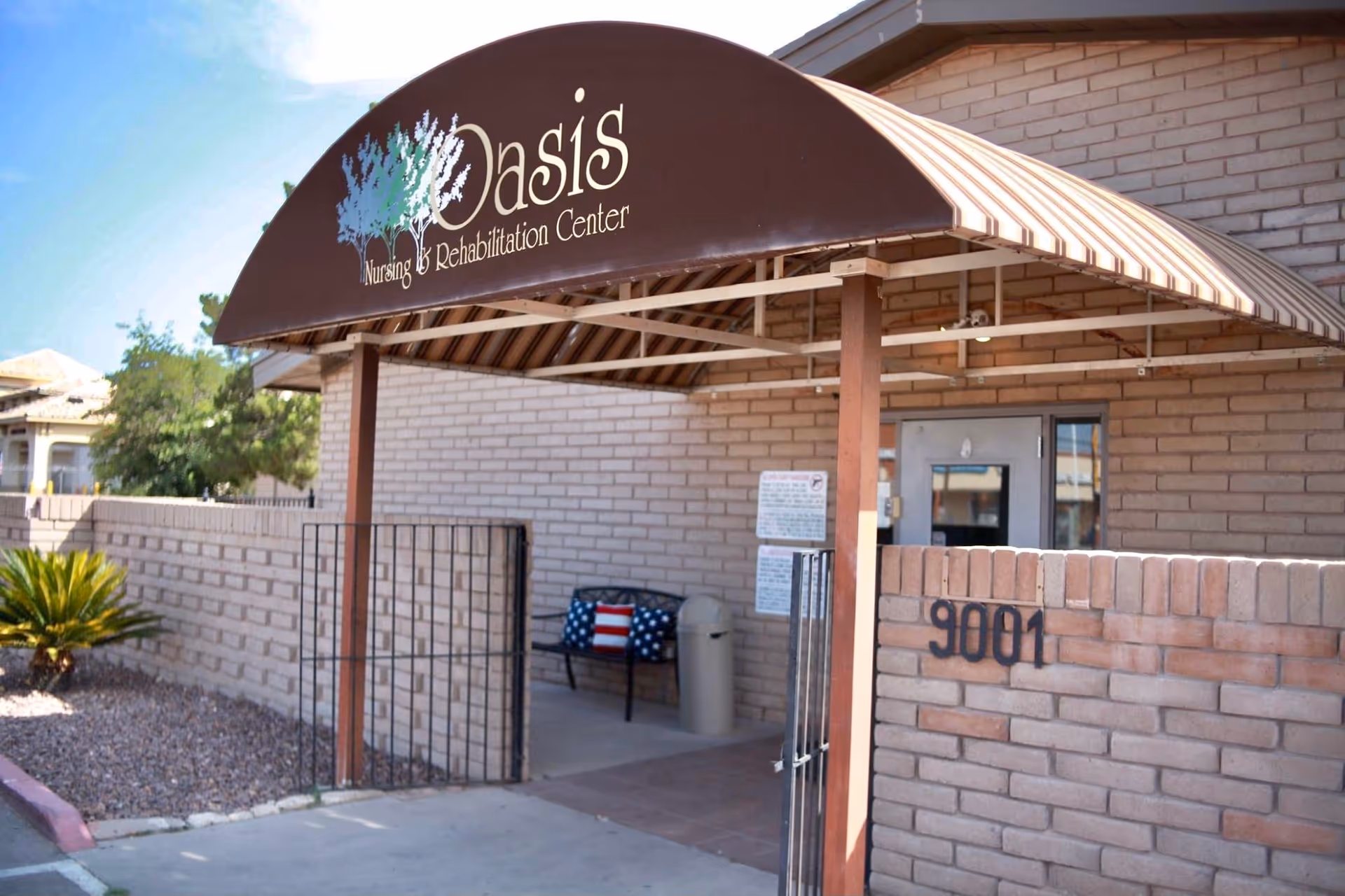 Exterior view of Oasis Nursing and Rehabilitation Center entrance with brown curved awning and brick wall
