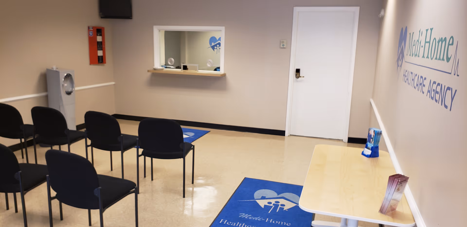 Waiting area with black chairs, a reception window, and Medi-Home Healthcare Agency sign.