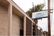 Exterior view of Del Mar Convalescent Hospital building with sign and palm trees.