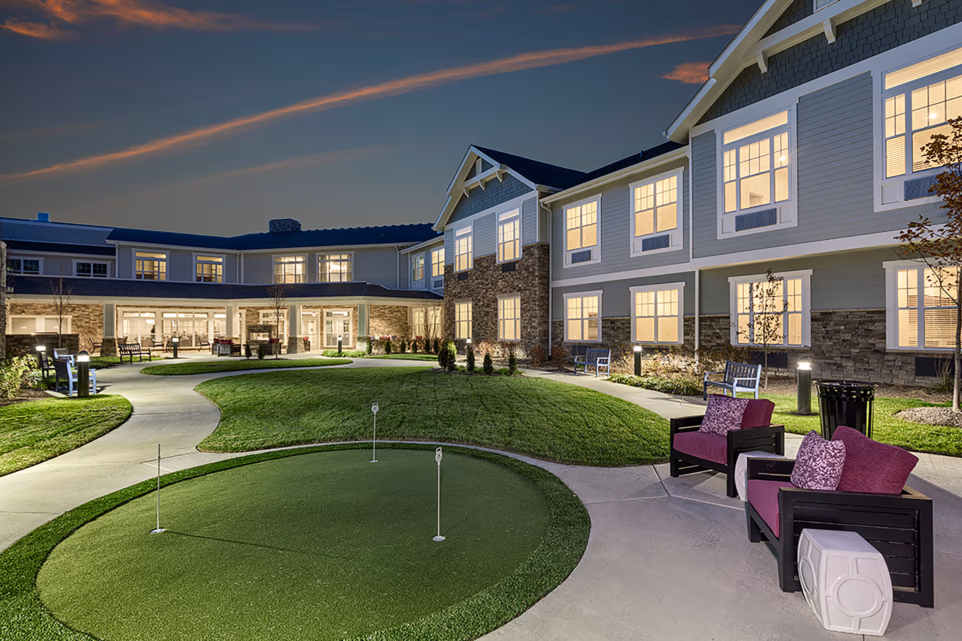 Evening exterior view of The Commons on Meridian, showing lit windows, courtyard, and outdoor seating.