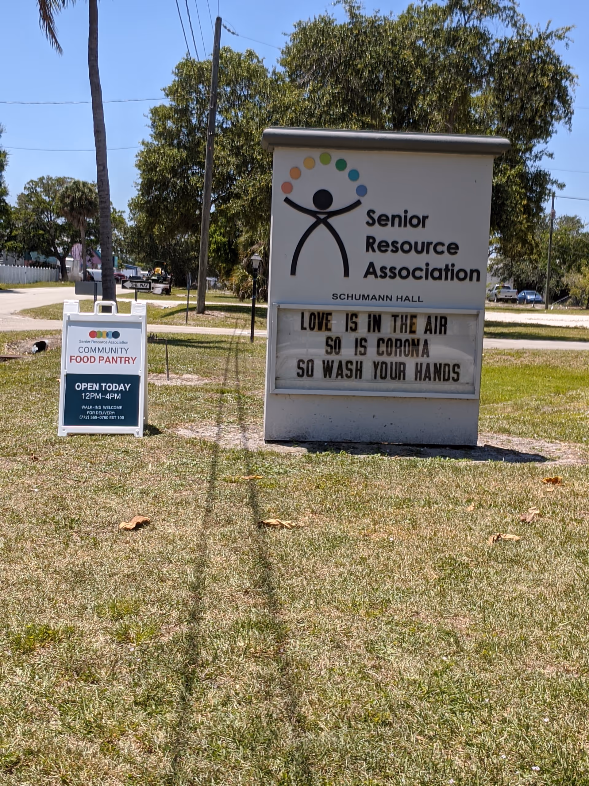 Exterior lawn area featuring a large Senior Resource Association sign and a smaller pantry sign.