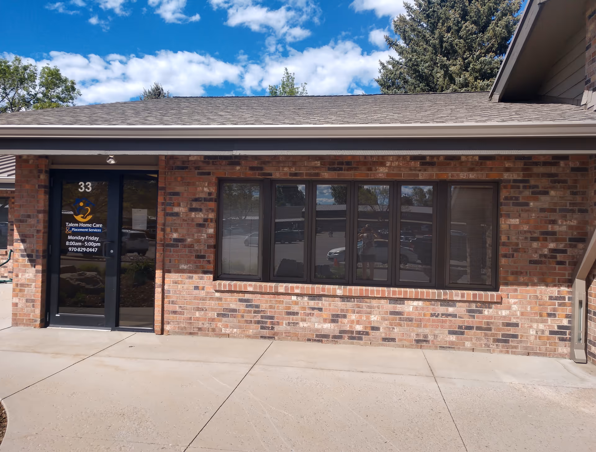 Brick exterior of Talem Home Care entrance with glass door and large windows.
