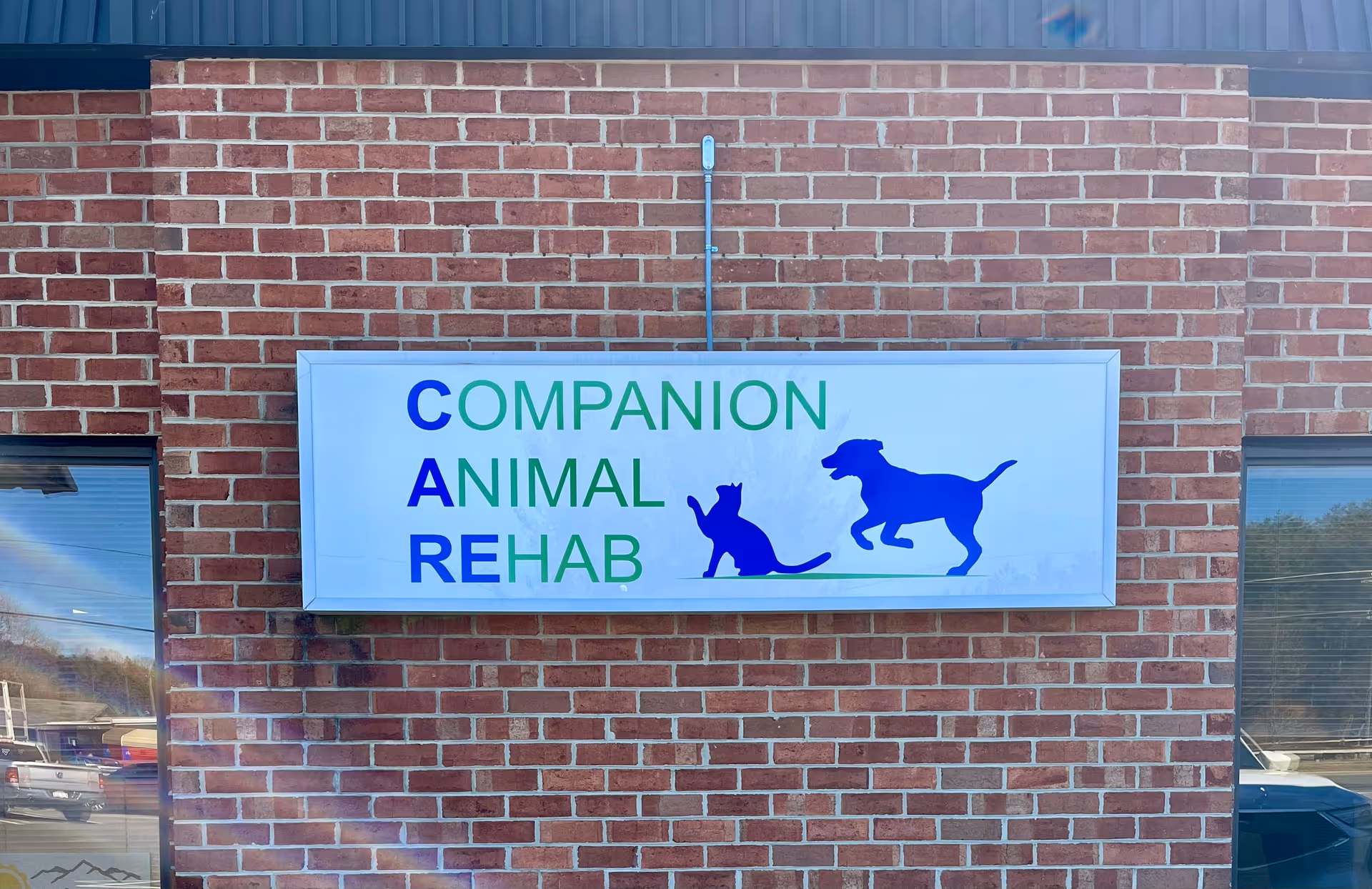 Exterior brick wall with a Companion Animal Rehab sign and dog and cat silhouettes.