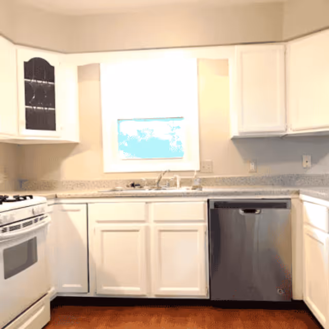 Bright white kitchen with cabinets, sink, and stainless dishwasher.