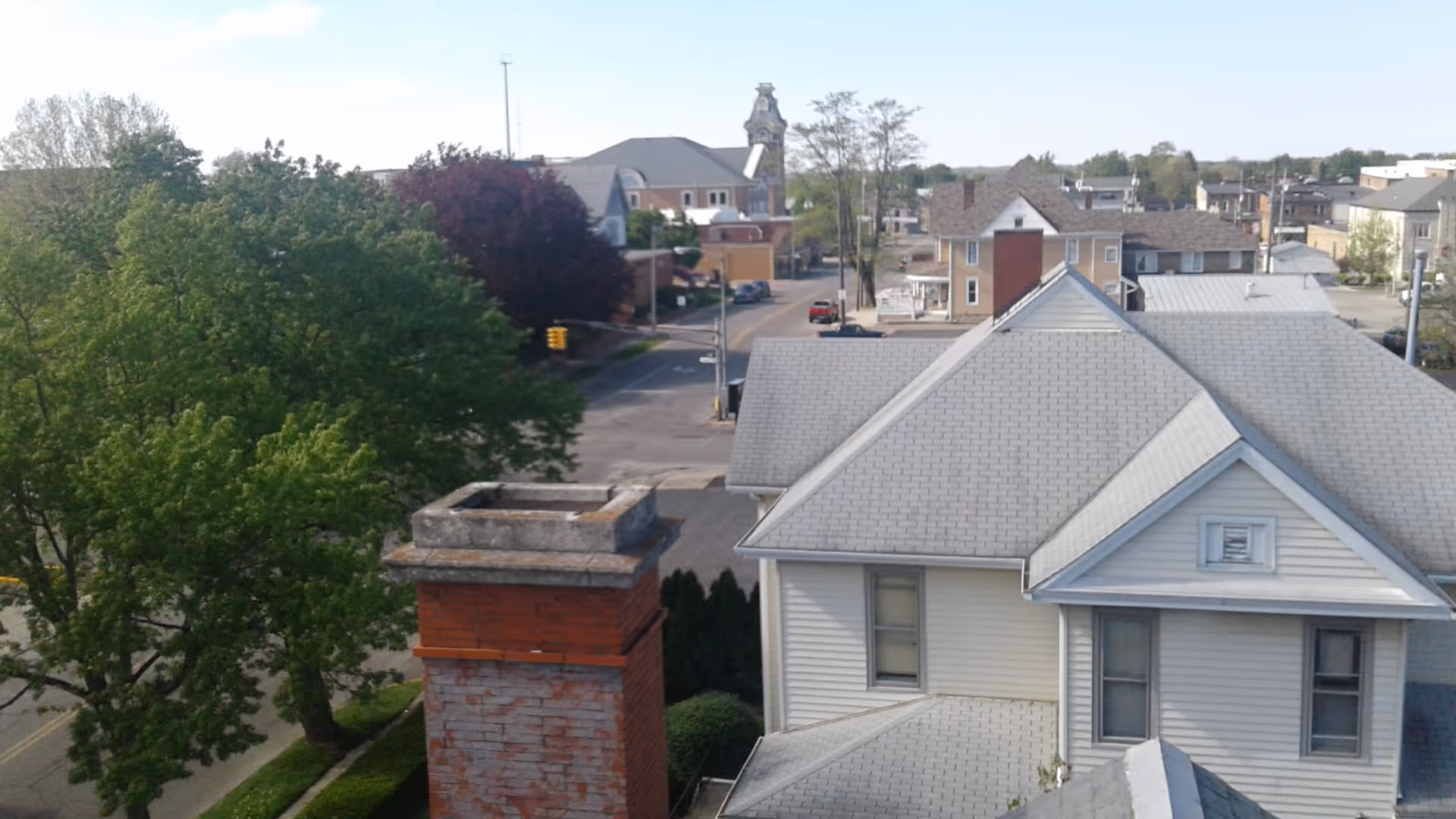 Aerial view of rooftops, trees, and a street in a small town.