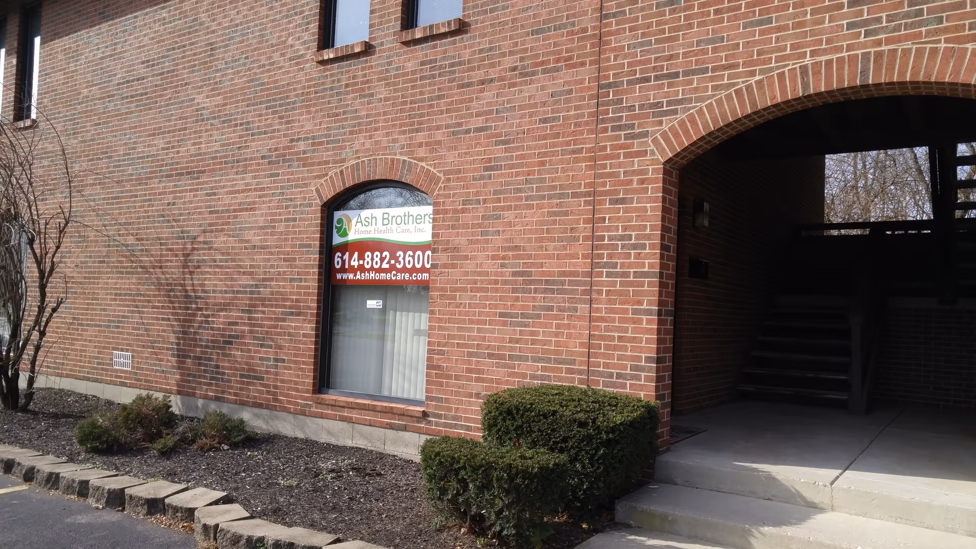 Brick building exterior with Ash Brothers Home Health Care window sign and entrance arch