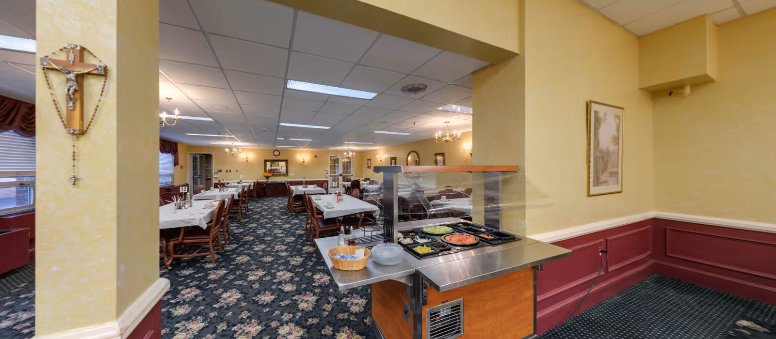 A spacious dining hall with many tables, chairs, and a salad bar display.