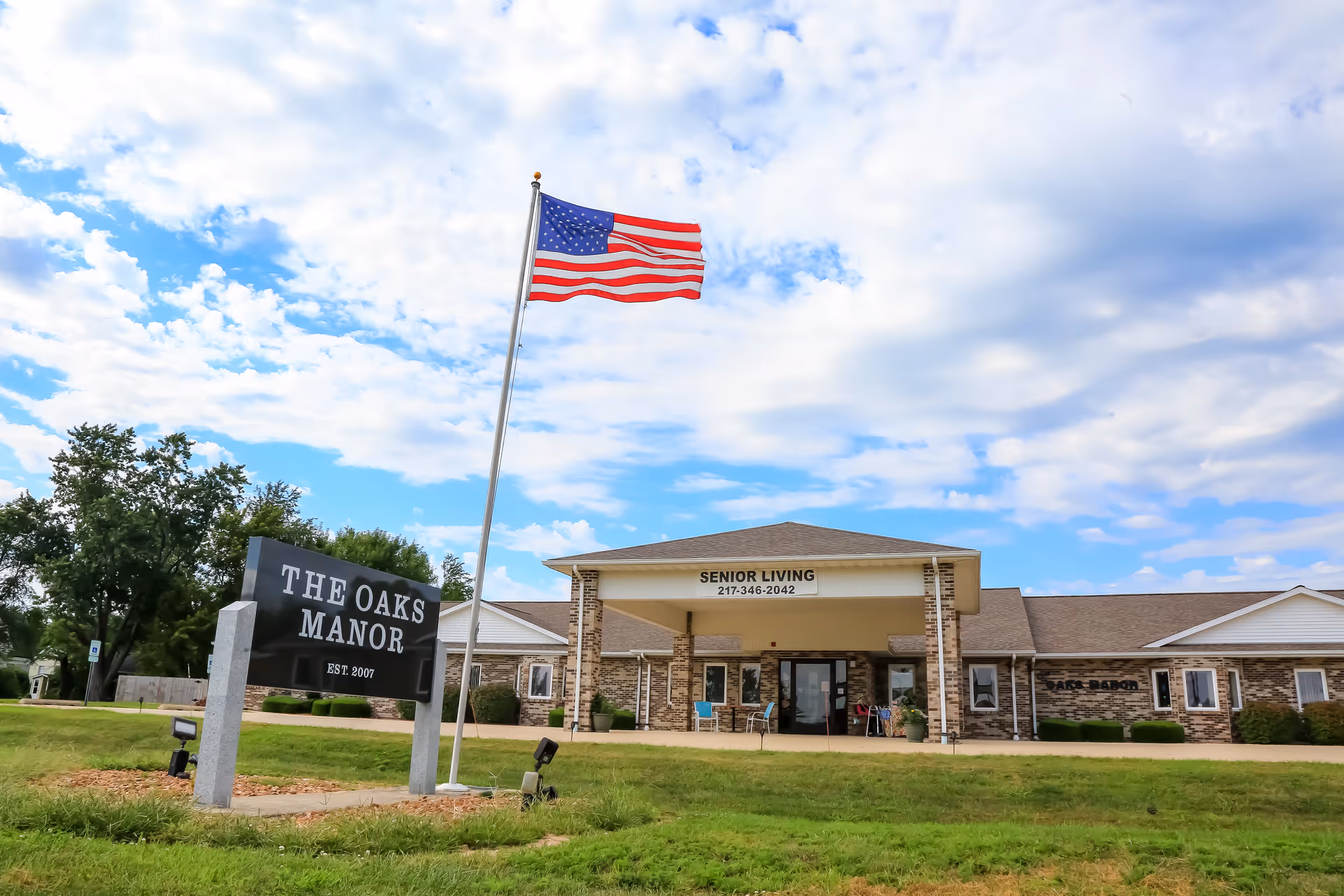 Exterior view of The Oaks Manor front entrance with American flag.