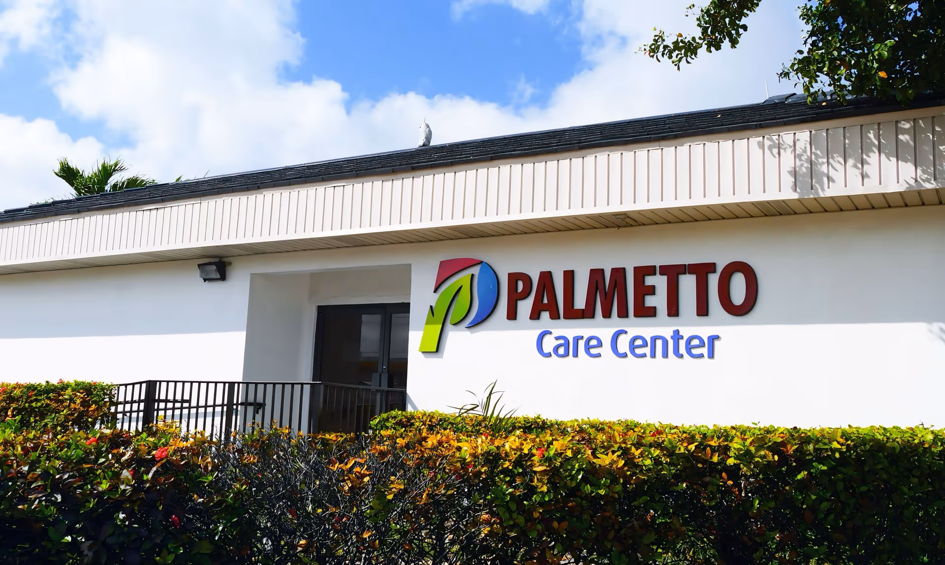 Front of Palmetto Care Center building with sign and trimmed hedges