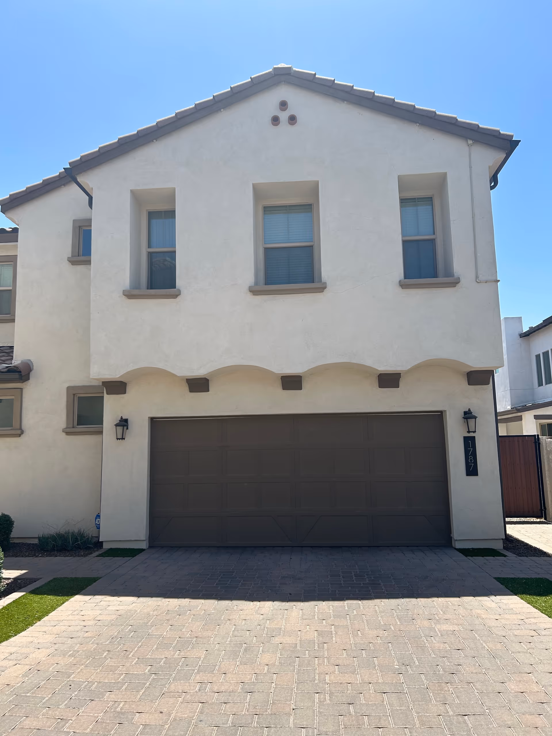 Front exterior of a two-story beige residential building with a large dark garage door