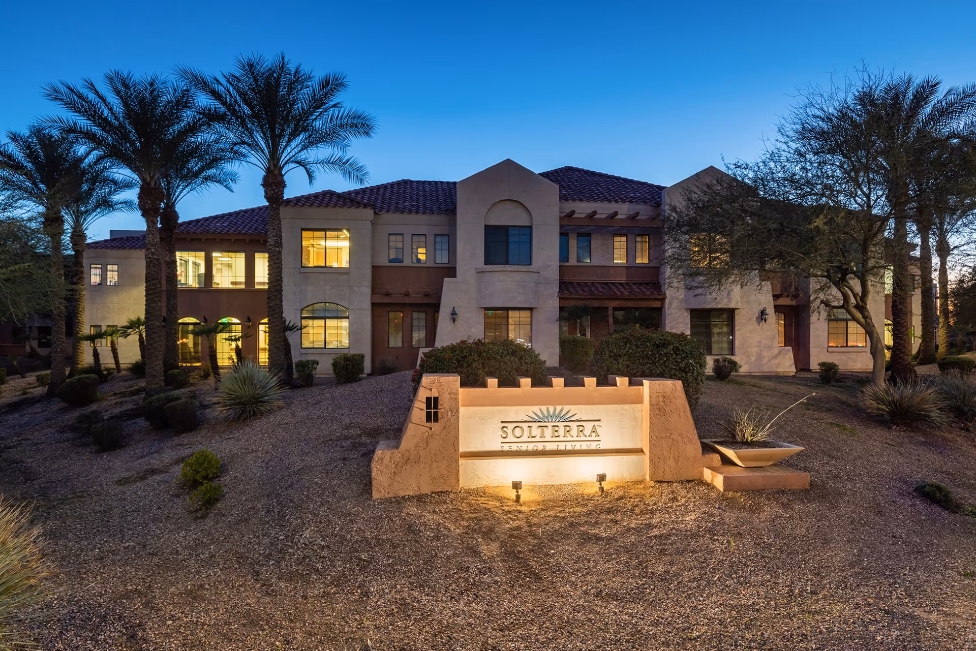 Exterior view of Solterra Senior Living building with illuminated sign and desert landscaping.