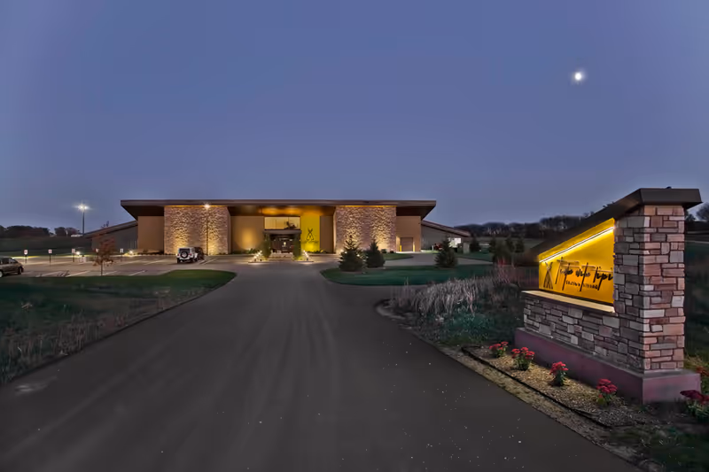 Exterior view of a senior living facility at dusk with a lit front entrance.
