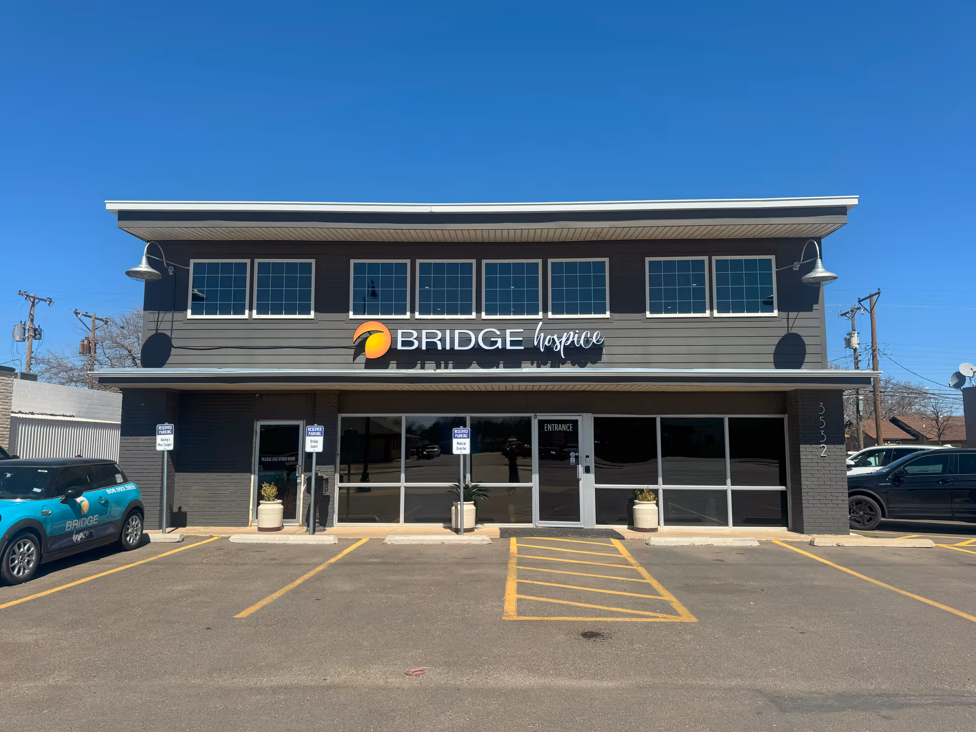 Exterior view of BRIDGE Hospice building with parking lot and glass entrance doors.