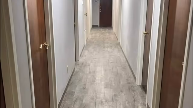 Narrow, well-lit interior hallway with multiple doors on both sides.