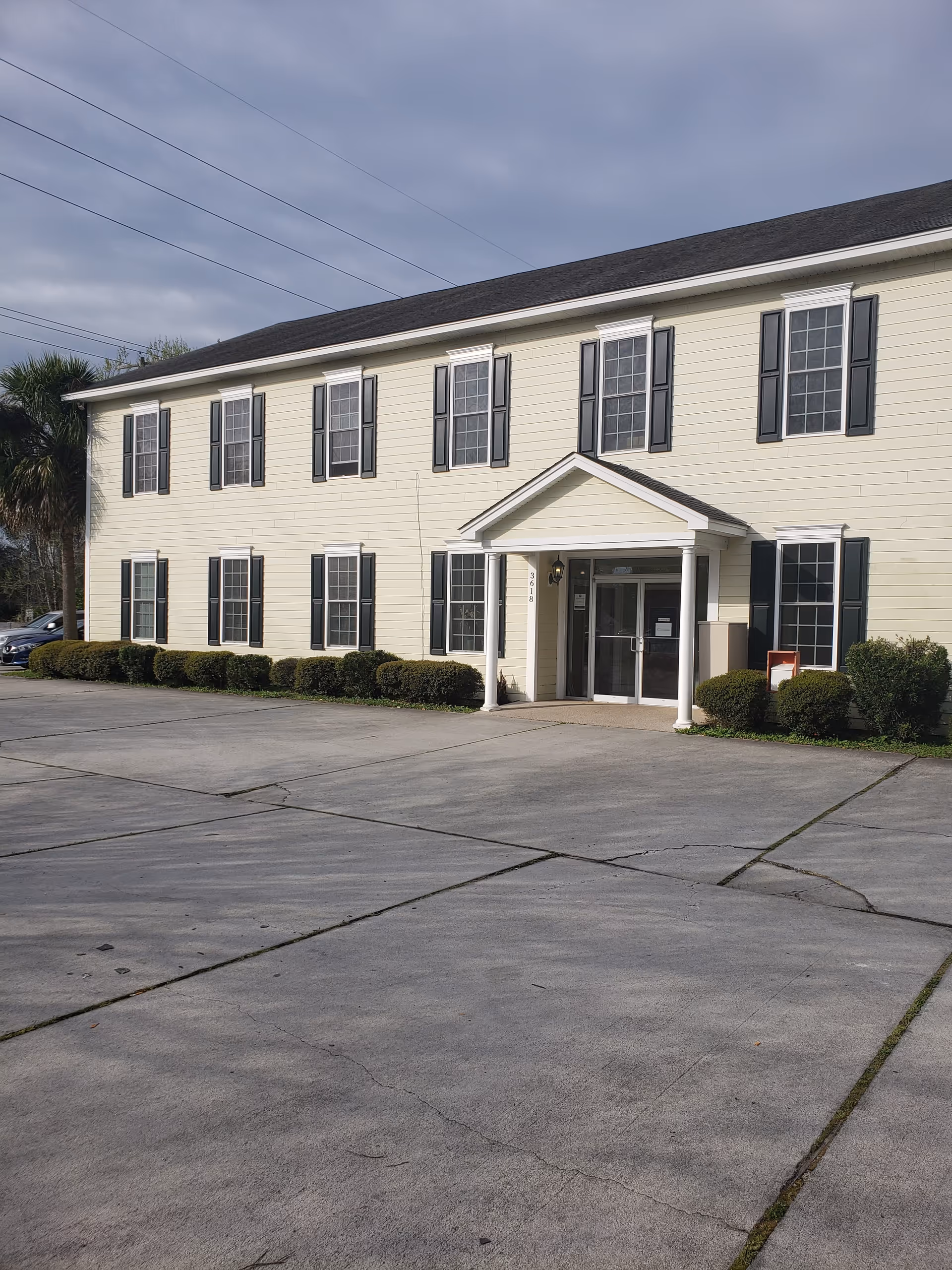 Exterior view of a two-story beige senior living building with a portico entrance.