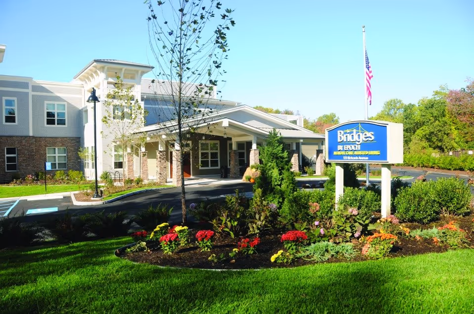 Exterior view of Bridges by EPOCH at Norwalk with landscaped entrance and sign.