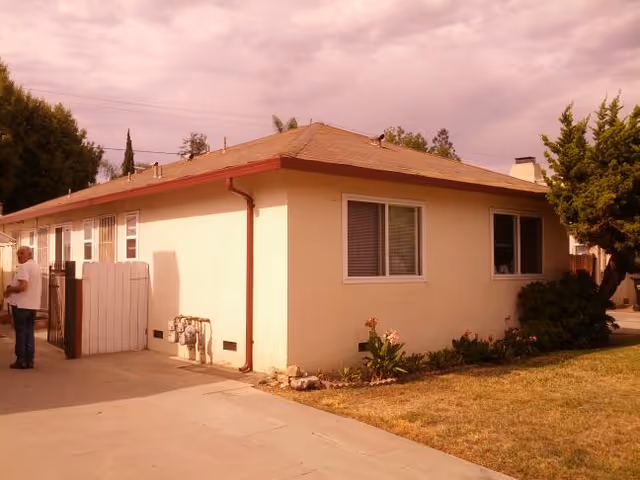 Single-story beige care home exterior with red trim and small yard.