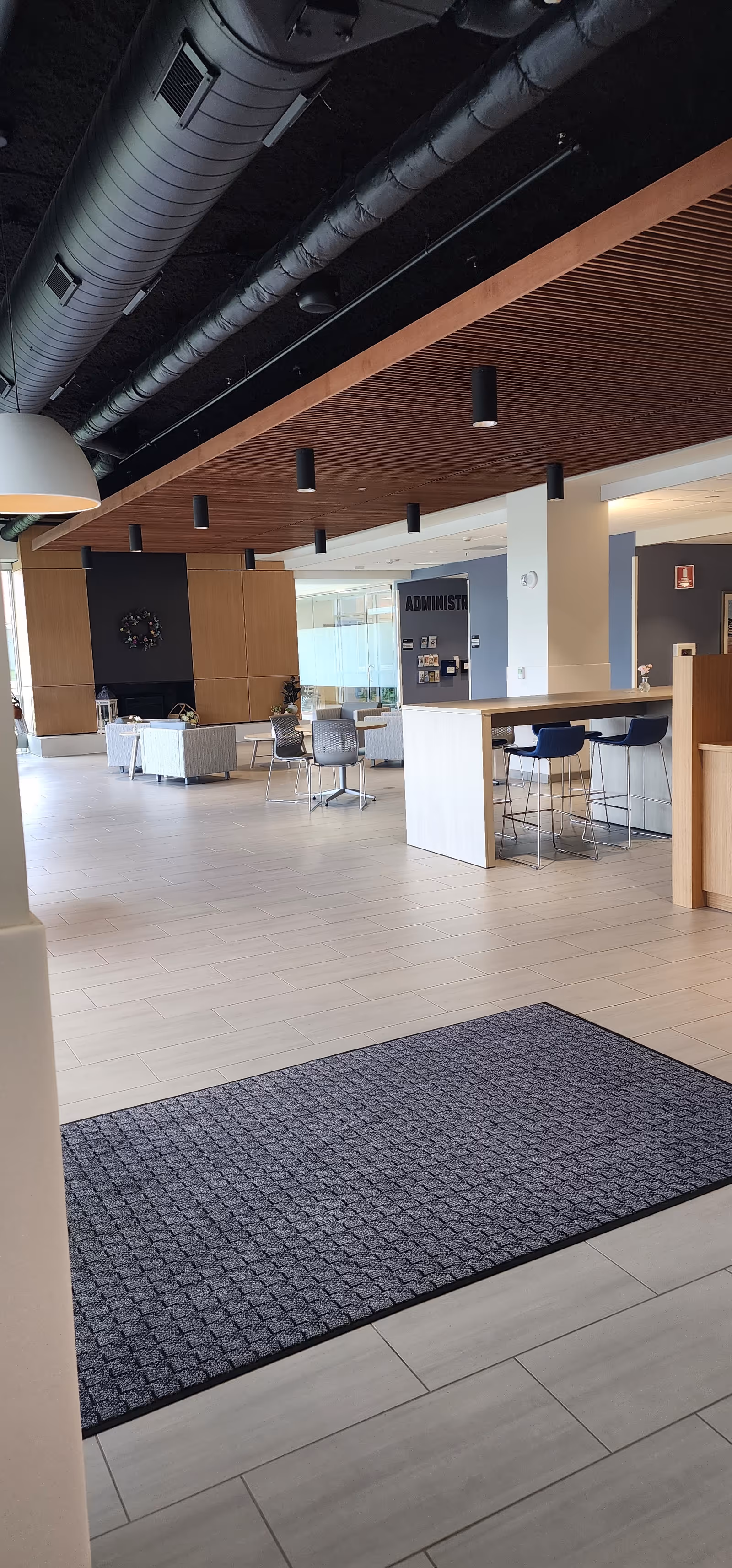 Modern lobby area with a high reception counter, seating, and exposed ductwork ceiling.