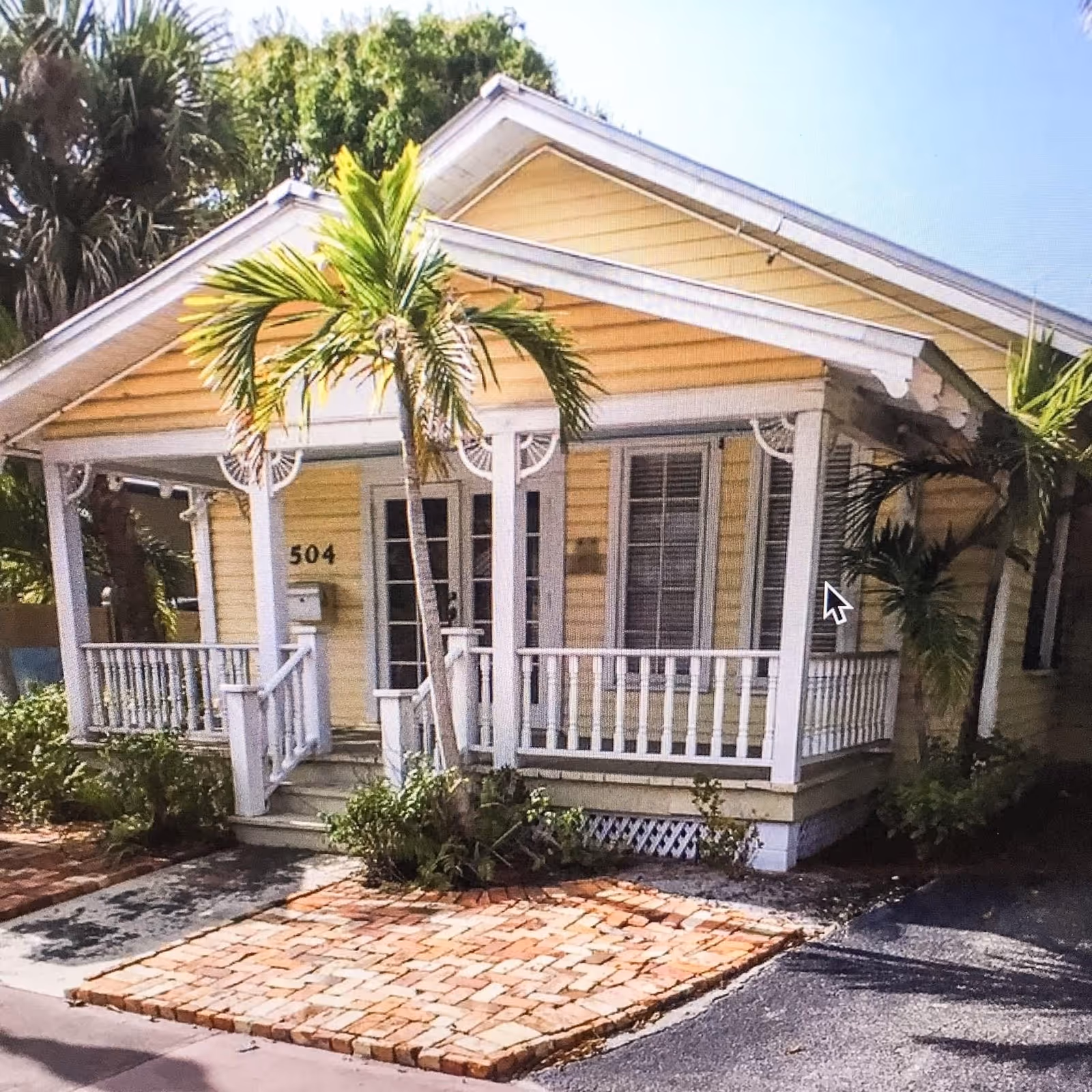 Acorn Elder Care facility exterior: yellow house with white porch and palm trees.