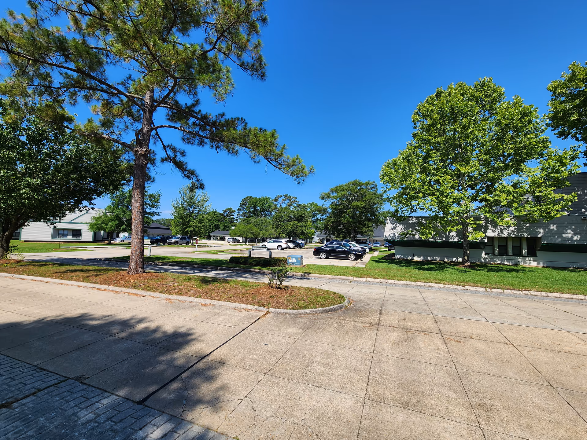 Exterior view of Caravelle Care facility with trees, parking lot, and blue sky.