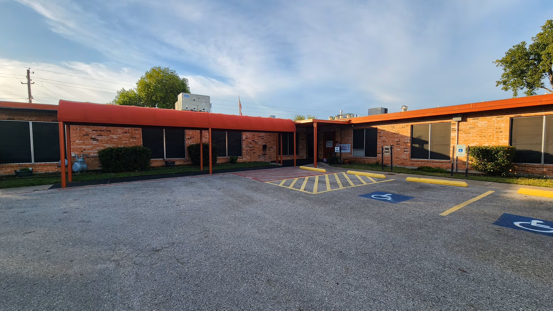 Front view of a brick senior living center with a red canopy and accessible parking