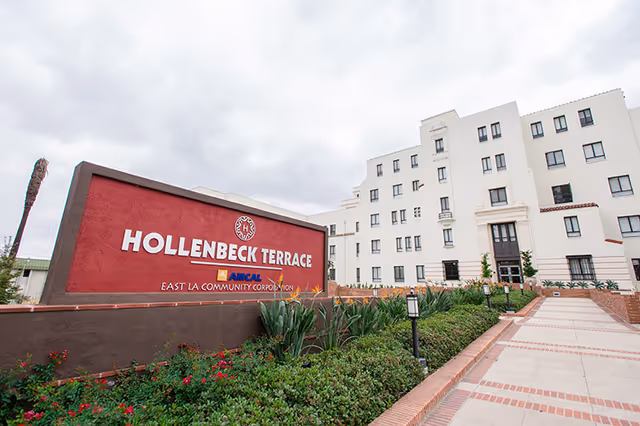 Exterior view of Hollenbeck Terrace with sign and a white building.
