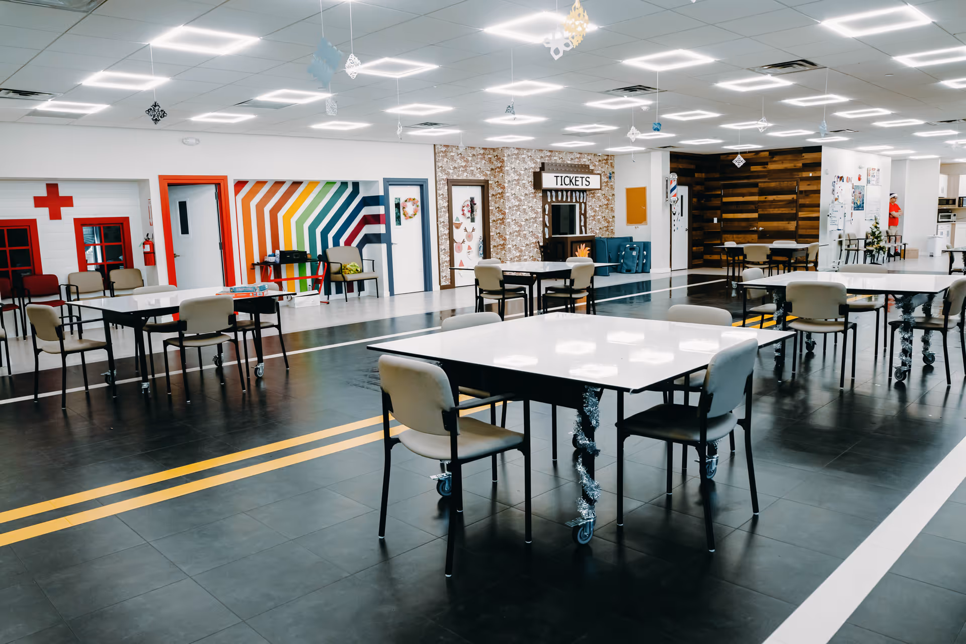 Bright, open activity area with tables, chairs, and colorful wall decor inside a senior facility.