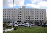 Exterior view of a large multi-story senior living building with a parking lot.