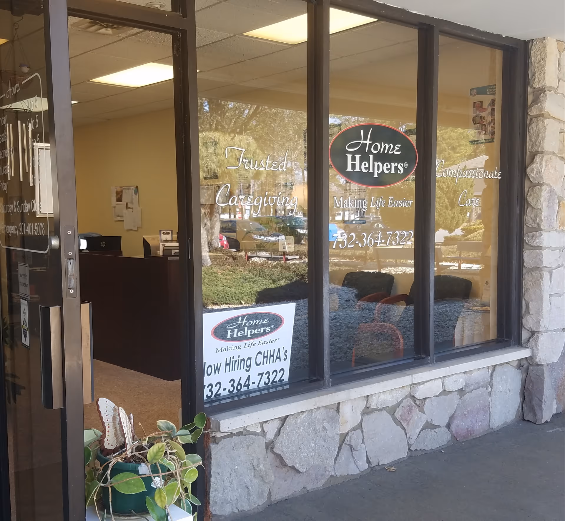 Glass storefront with Home Helpers sign and stone facade, showing a reception desk inside.
