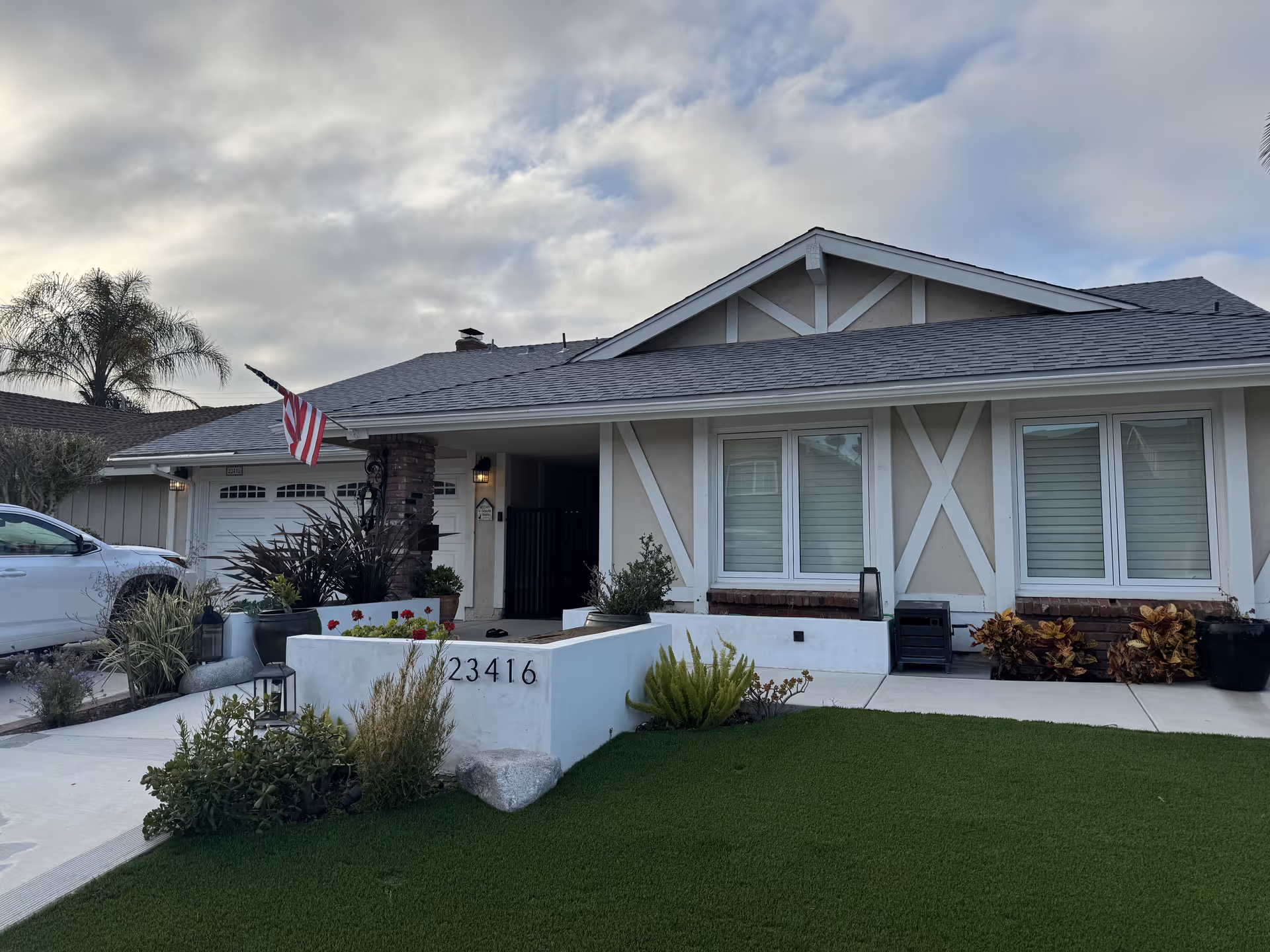 Front view of Devonshire Cottage, a single-story senior living home with lawn and flag.