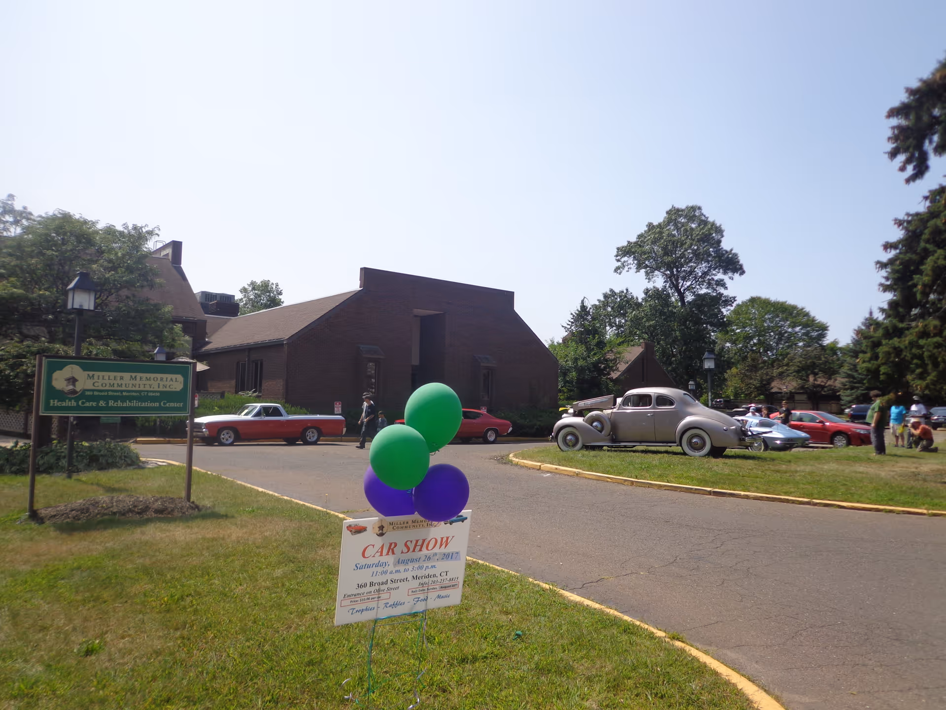 Exterior view of Meriden Health and Rehab building with a car show and balloons.