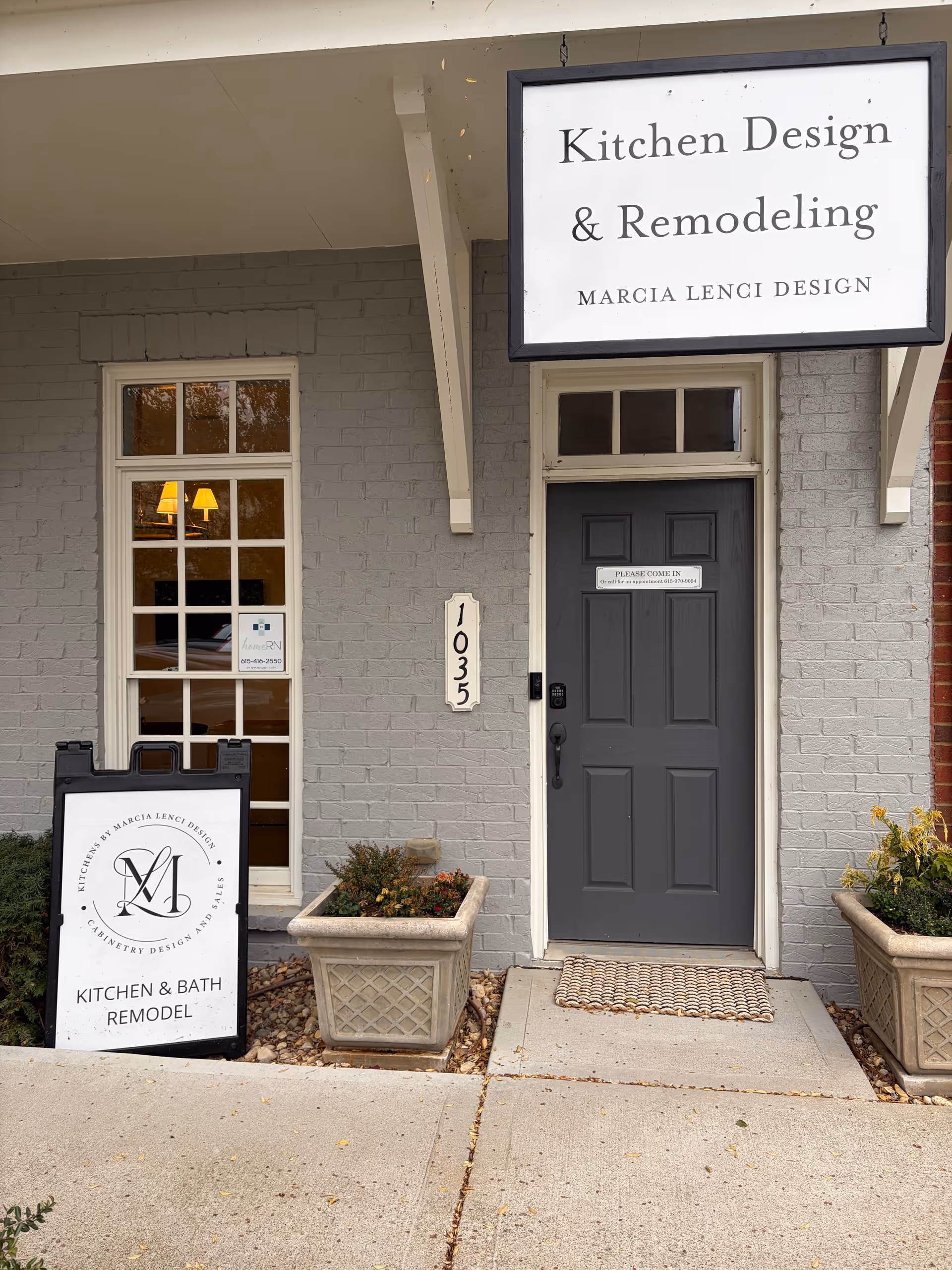 Exterior view of a building entrance with a sign reading Kitchen Design and Remodeling.