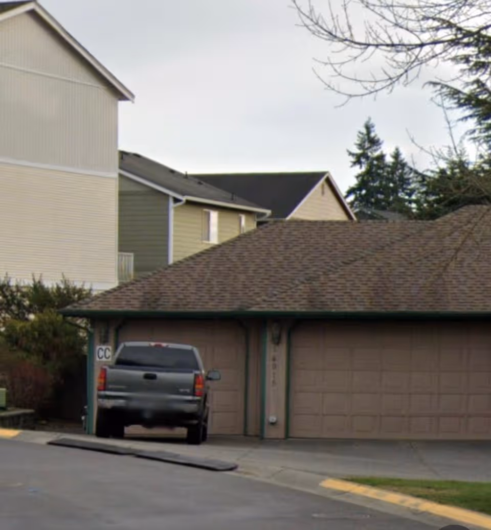 Residential building exterior with a brown garage door and a parked pickup in driveway