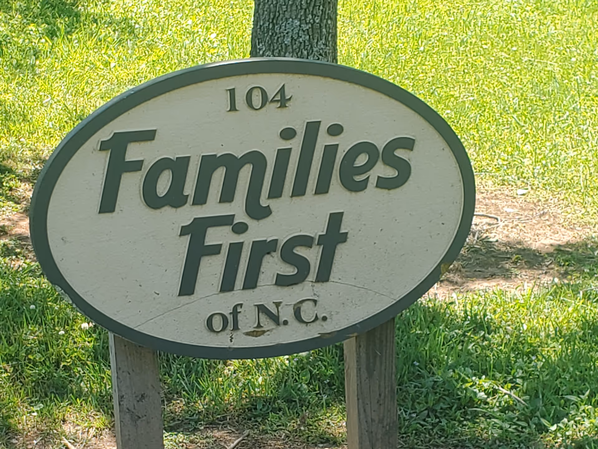 Oval sign reads 'Families First of N.C.' on a grassy outdoor area.