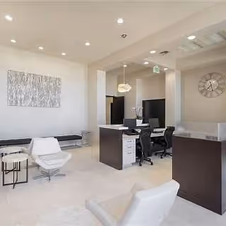 Bright modern lobby with white seating, a reception desk, and abstract wall art.
