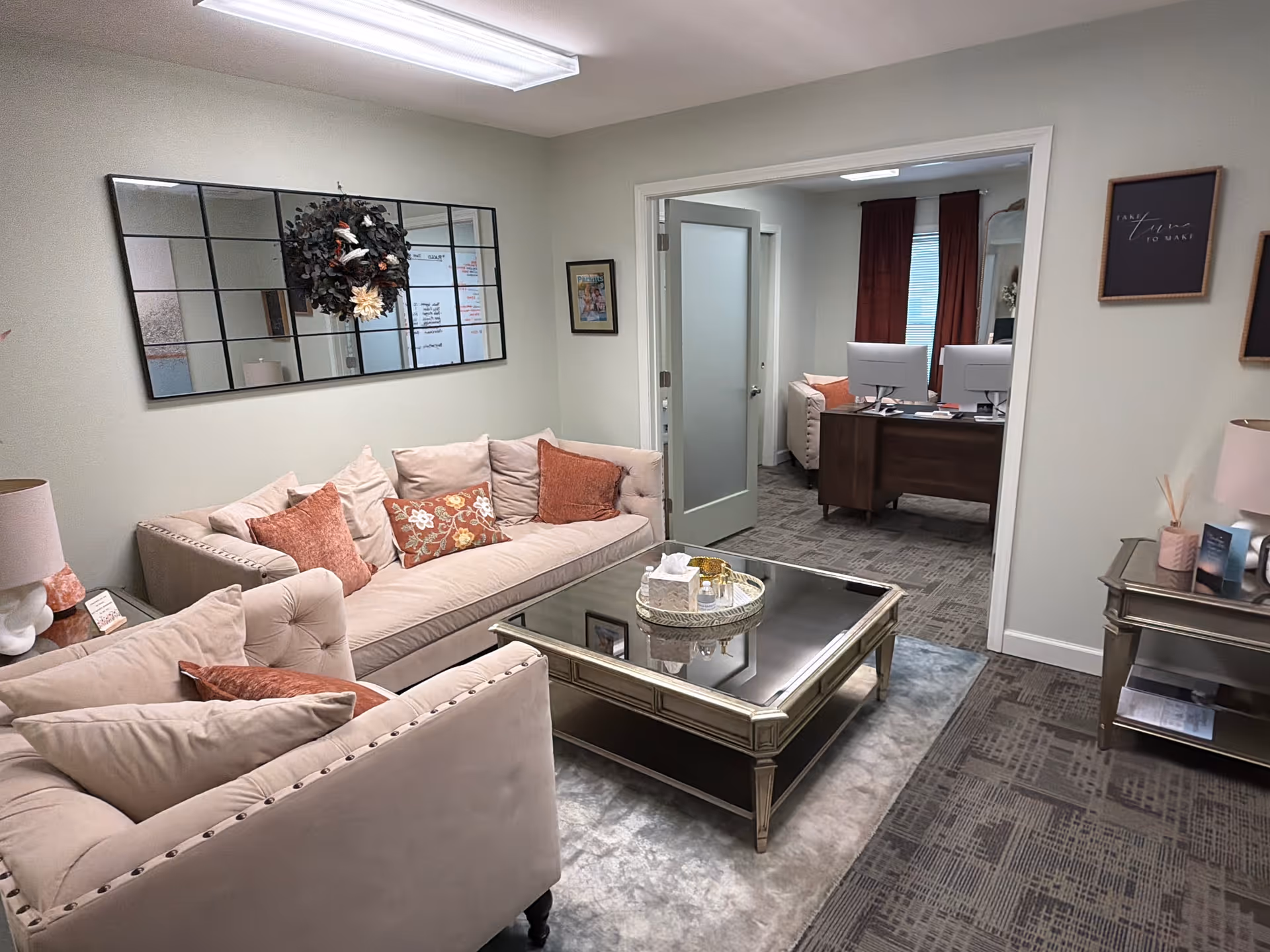 Cozy beige lounge with tufted sofas, decorative pillows, and a glass coffee table.