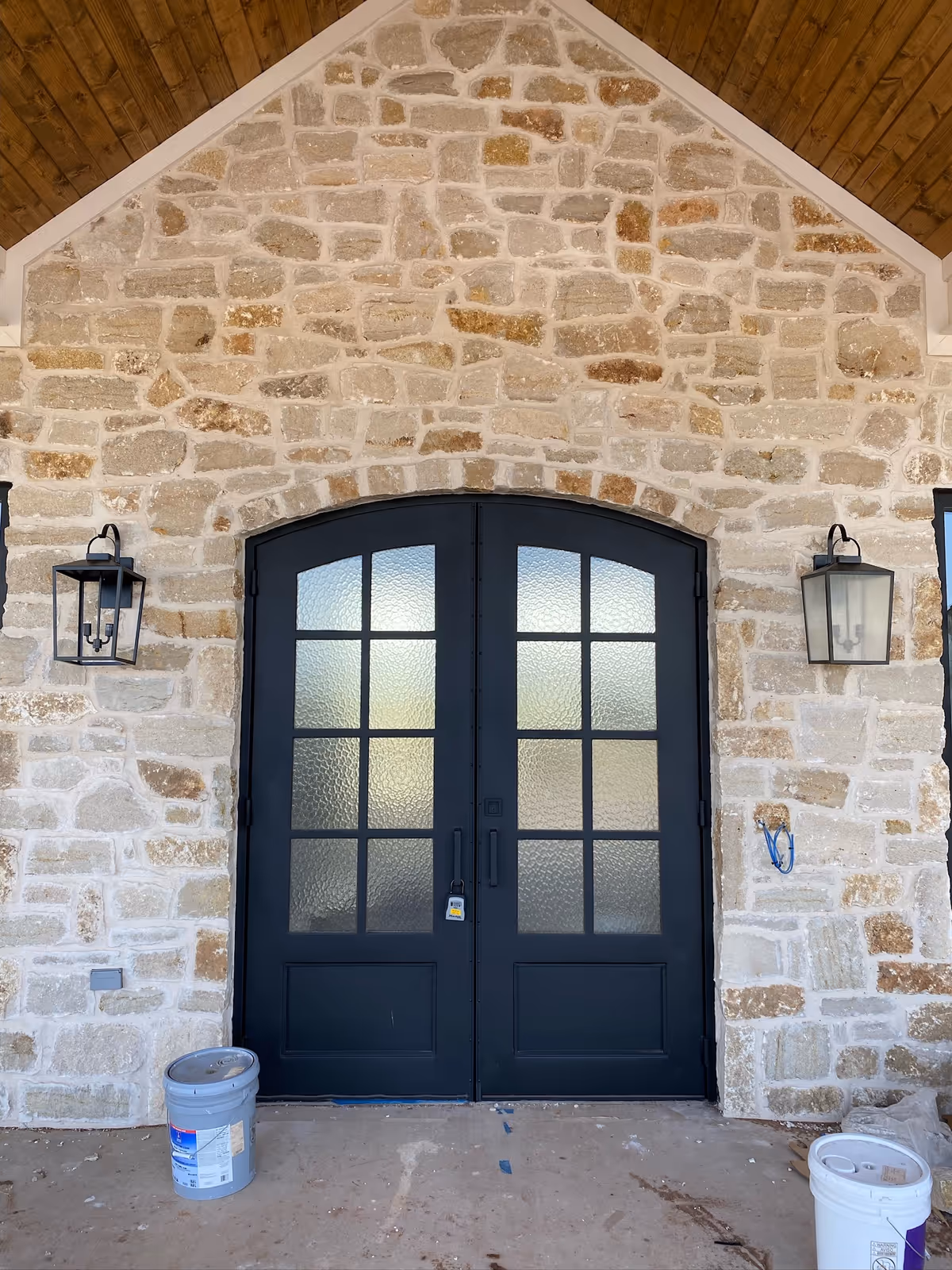 Stone facade with arched double doors, two lanterns, and a front entrance.